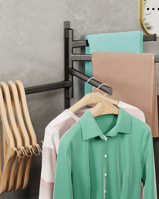 Black towel rack with clothes and hangers against a gray wall.